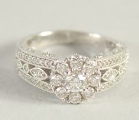 AN 18CT WHITE GOLD AND DIAMOND CLUSTER RING, with diamond set shoulders and bezels.