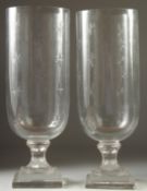 A PAIR OF GLASS STORM LAMPS with stars on a square base. 15.5ins high.