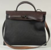 A HERMES OF PARIS BROWN LEATHER BAG AND BLACK FABRIC BAG with long leather handle. 12ins long, 10ins