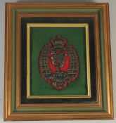 A FRAMED AND GLAZED ROYAL IRISH RIFELS BADGE.