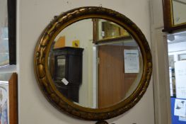 A large gilt framed oval mirror.