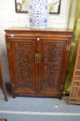 A good Chinese hardwood two door cupboard with intricately carved panelled doors.