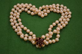 A three row pearl necklace with 9ct gold and gem set clasp.