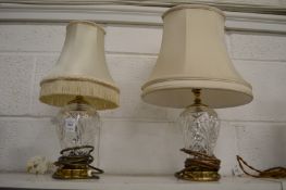 A pair of cut glass and brass table lamps (differing shades).
