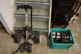 A battery powered golf bag trolley and batteries.