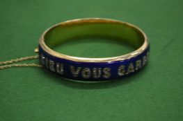 A yellow metal blue enamel and gem set hinged bangle 'Dieu Vous Garde'.