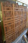 An Eastern carved and pierced hardwood four panelled dressing screen with inlaid brass decoration.