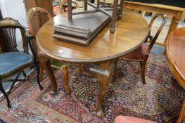 An Edwardian mahogany oval extending dining table with two leaves on carved cabriole legs.
