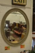 An oval mirror with decorative grey painted frame.