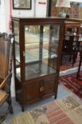 A Chinese hardwood display cabinet with two panelled cupboard doors below.