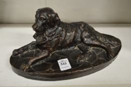 A bronze effect model of a reclining dog.