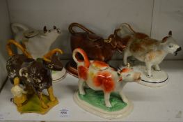 Five various pottery cow creamers.