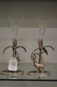 A pair of plated bud vases, the bases modelled as deer by a tree, each with engraved glass posy