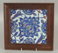 AN IZNIK STYLE FRAMED POTTERY TILE, 25.5cm x 26.5cm overall.
