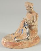 AN OTTOMAN TERRACOTTA SEATED FIGURE, on oval base, 14cm long.
