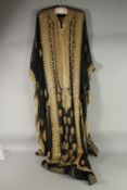 AN ARAB LADIES BLACK SATIN AND GOLD THREAD DECORATED DRESS.