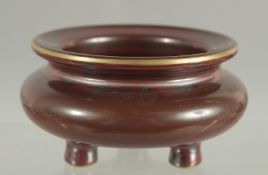 A SMALL CHINESE MOTTLED RED GLAZE PORCELAIN TRIPOD CENSER, with gilt highlights and character