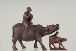 A CHINESE CARVED WOOD FIGURE OF A MAN UPON AN OXEN, together with a smaller similar figure, (2).