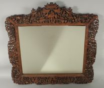 A FINE CHINESE CANTON CARVED AND PIERCED WOOD MIRROR, the frame of the mirror decorated with typical