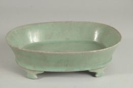 A CHINESE CELADON GLAZE OVAL-FORM PLANTER, raised on four feet, 22.5cm long.
