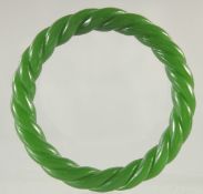A CARVED GREEN JADE TWIST BANGLE. 3ins diameter.