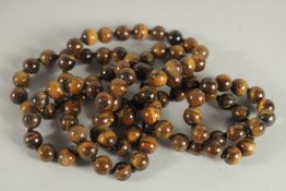 A STRING OF TIGER'S EYE BEADS. 38ins long.