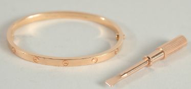 A CARTIER .750 GOLD LOVE BANGLE AND KEY in a fitted red Cartier pouch.