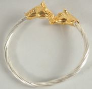 A STERLING SILVER TWISTED BANGLE with gilded horse head terminals.