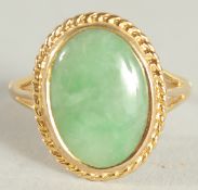 A YELLOW GOLD JADE OVAL RING.