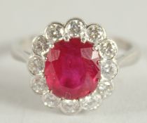 AN 18 CARAT WHITE GOLD, RUBY AND DIAMOND CLUSTER RING. Ruby 3 carats +.