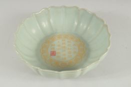 A CHINESE PETAL SHAPE CELADON BOWL, the interior with characters. 21cm diameter.