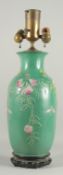 A CHINESE GREEN GROUND PORCELAIN LAMP on a wooden stand. 16ins high.