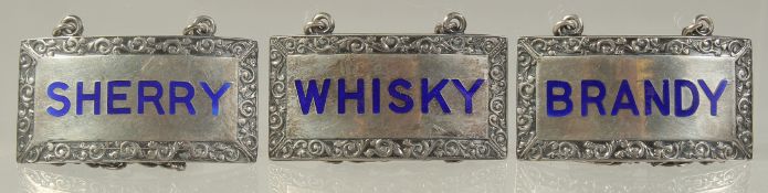 THREE SILVER AND ENAMEL WINE LABELS: SHERRY, BRANDY, WHISKY.