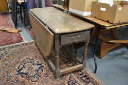 An early oak drop leaf gateleg dining table with a drawer to one end.