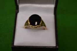 A 9ct gold ring of open work design set with an oval black stone.