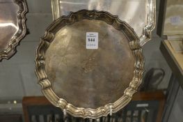 A small silver salver with shaped border on four scroll feet, the centre engraved with initals.