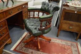 A green leather button upholstered mahogany framed desk chair.