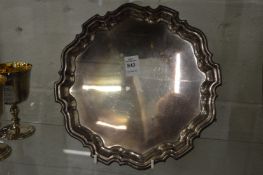 A silver salver with shaped rim on three scroll feet.
