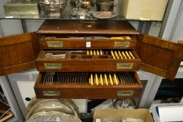 An oak table top canteen of cutlery, the pair of doors opening to reveal three drawers.