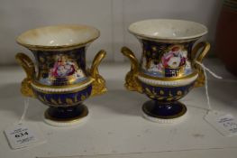 A pair of gilt and floral decorated twin handled small vases.