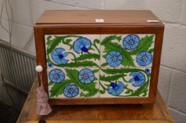 A teak table top cabinet, the door applied with Arts and Crafts style tiles.