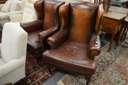 A pair of leather upholstered Georgian style wing armchairs.