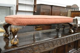 A long foot stool on carved cabriole legs.