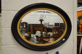 A Victorian style oval ebonised and gilt framed wall mirror.