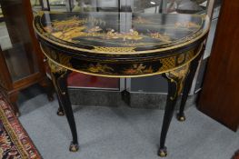 A chinoiserie decorated black lacquer demi-lune fold-over card table.