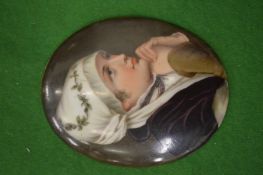 An oval porcelain plaque depicting a woman at prayer.