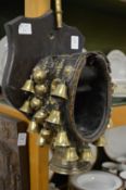 A rare and unusual goat collar with numerous brass bells mounted on an oak shield shape plaque.
