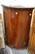 A mahogany bow front hanging corner cupboard.