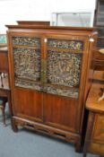 A Chinese two door cupboard with carved and gilt decorated panelled doors.