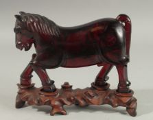 A RARE CHINESE BAKELITE -POSSIBLY CHERRY AMBER HORSE on original wooden stand, horse 21cm long,